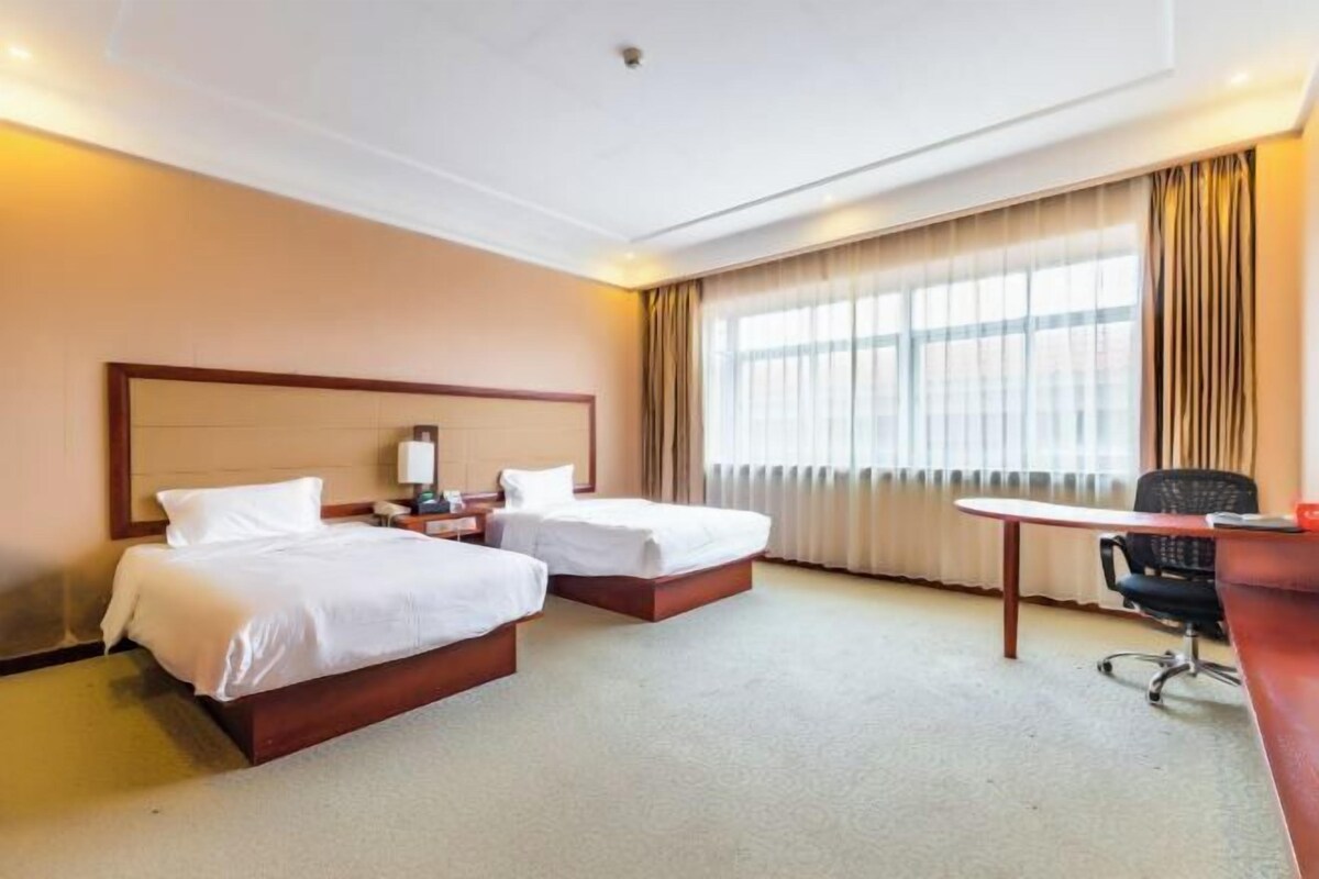 A hotel room with two beds, a desk, and a chair.