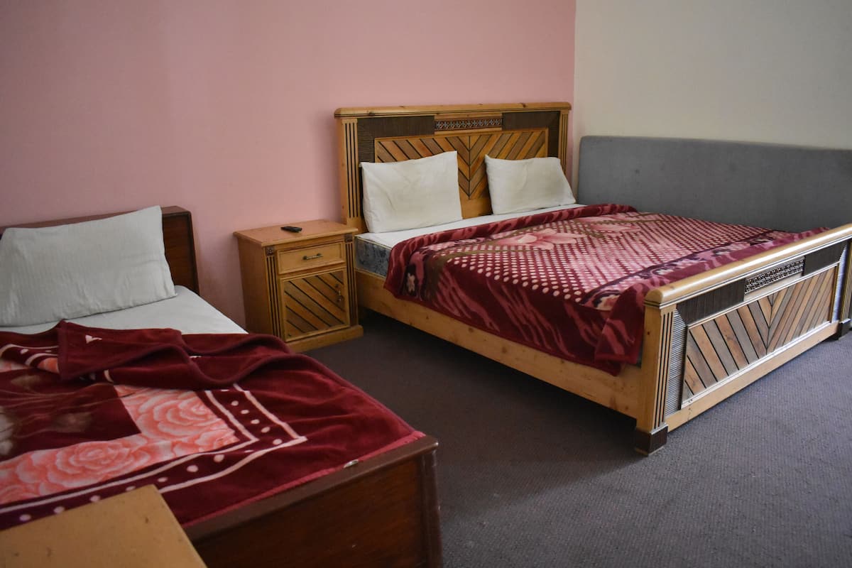 A bedroom with two single beds, a nightstand, and a dresser.