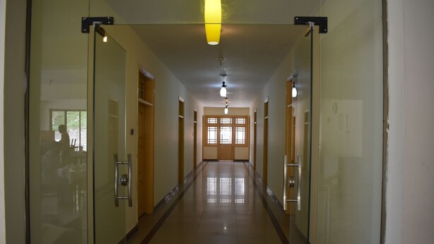 A long, narrow hallway with glass doors on both sides, leading to a room with a large window at the end. - Hotel Cedar Inn (Mansehra)