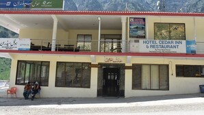 A hotel with a signboard for Hotel Cedar Inn & Restaurant, featuring a view of mountains in the background. - Hotel Cedar Inn (Mansehra)
