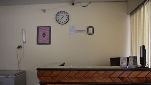 A reception desk with a clock, a framed religious symbol, and a sign indicating check-out time. - Hotel Cedar Inn (Mansehra)