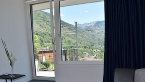 Una stanza con un'ampia finestra che si affaccia su un paesaggio montuoso.