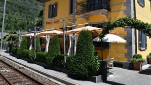 Un edificio giallo con un ristorante chiamato "Ristorante Stazzone" al piano terra. Sono presenti ombrelloni da esterno e piante in vaso.