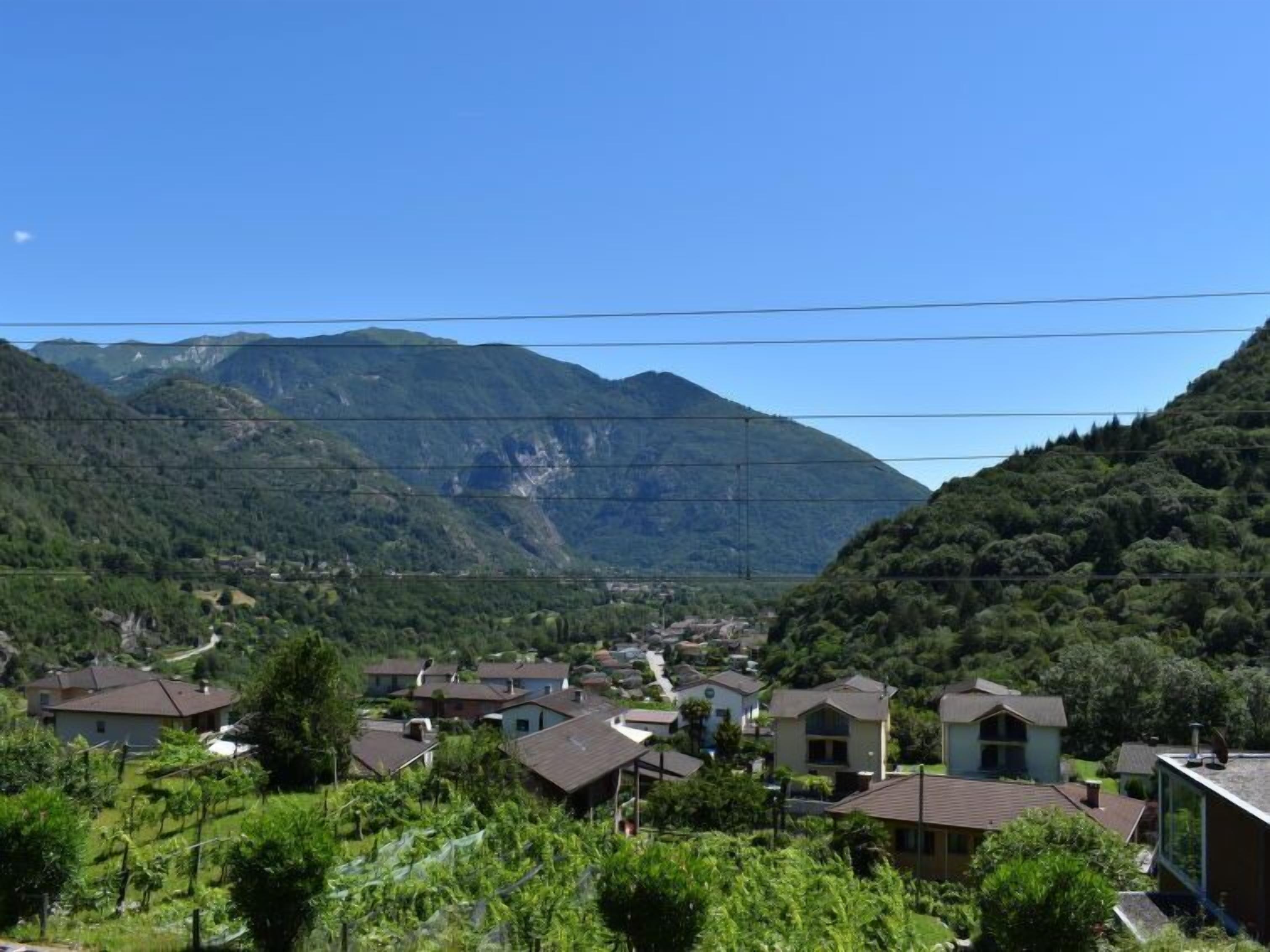 A residential area with houses, a valley, and mountains in the background.