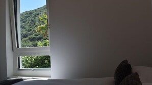 A bedroom with a bed, a window, and a view of a green landscape. - Capriccio 16 Pergola by Interhome (Intragna)