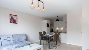 Una sala de estar moderna con un sofá, una mesa de comedor con sillas y una cocina al fondo.