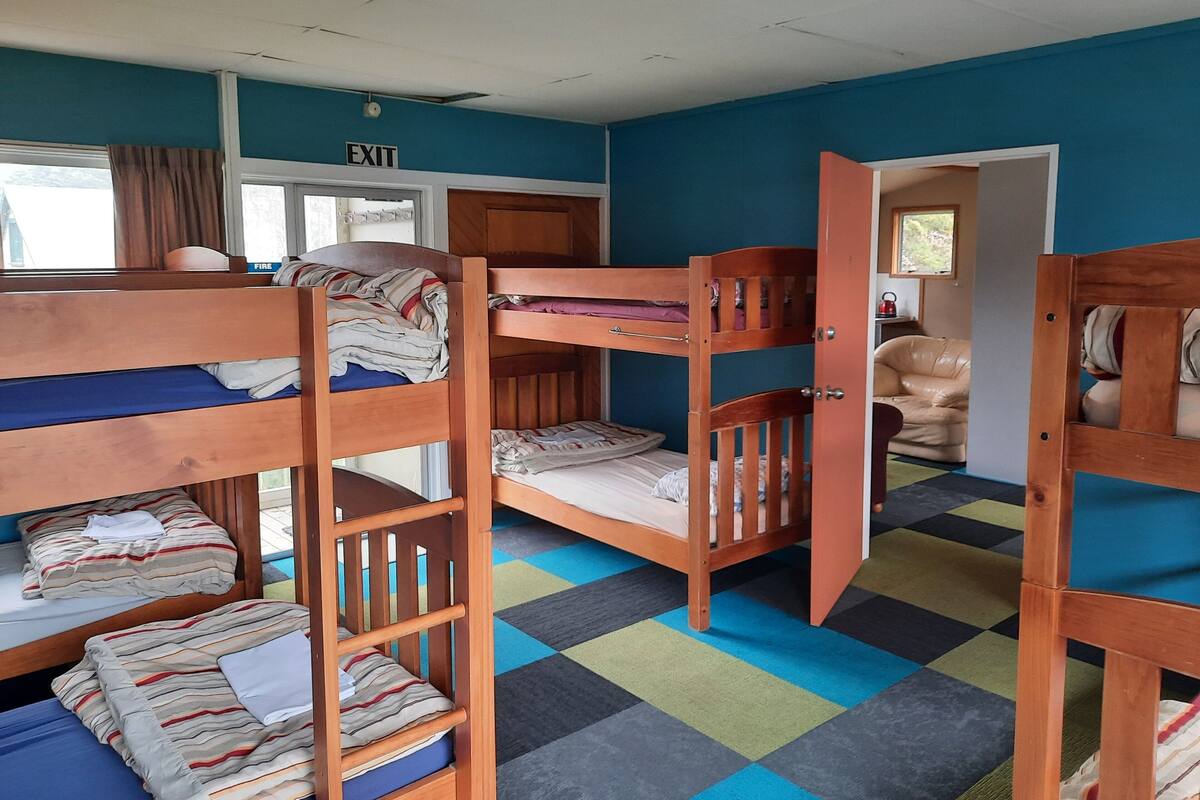 A dormitory room with bunk beds, a fire alarm, and a door to the outside.