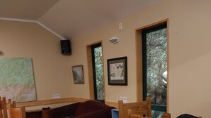 A room with a wooden table, a red sofa, and a large window.