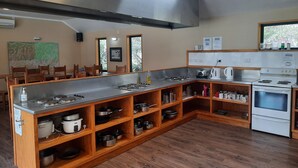 A kitchen with a long counter, wooden shelves, a stove, and a microwave.