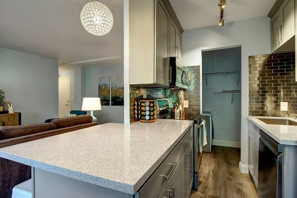A modern kitchen with a large island, stainless steel appliances, and a decorative wall backsplash.