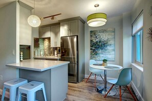 A modern kitchen with a central island, stainless steel appliances, and a dining area with a round table and chairs.