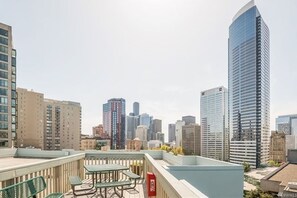 A rooftop terrace with outdoor seating and a view of a city skyline.
