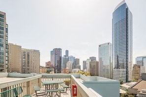 A rooftop terrace with outdoor seating and a view of a city skyline. - Modern 1B Downtown Condo near Convention Center (Seattle)
