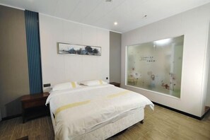 A hotel room with a bed, a nightstand, a wall-mounted artwork, and a large window with frosted glass. - Flying Fox Business Hotel (Zhangjiajie 72 Qilou Branch) (Zhangjiajie)