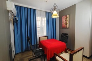 A room with a bed, a table with a red tablecloth, a chair, a desk, and a hanging light fixture. - Flying Fox Business Hotel (Zhangjiajie 72 Qilou Branch) (Zhangjiajie)