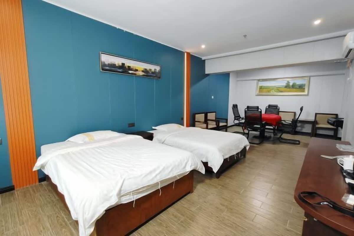 Quarto de hotel com duas camas, uma escrivaninha e uma cadeira.