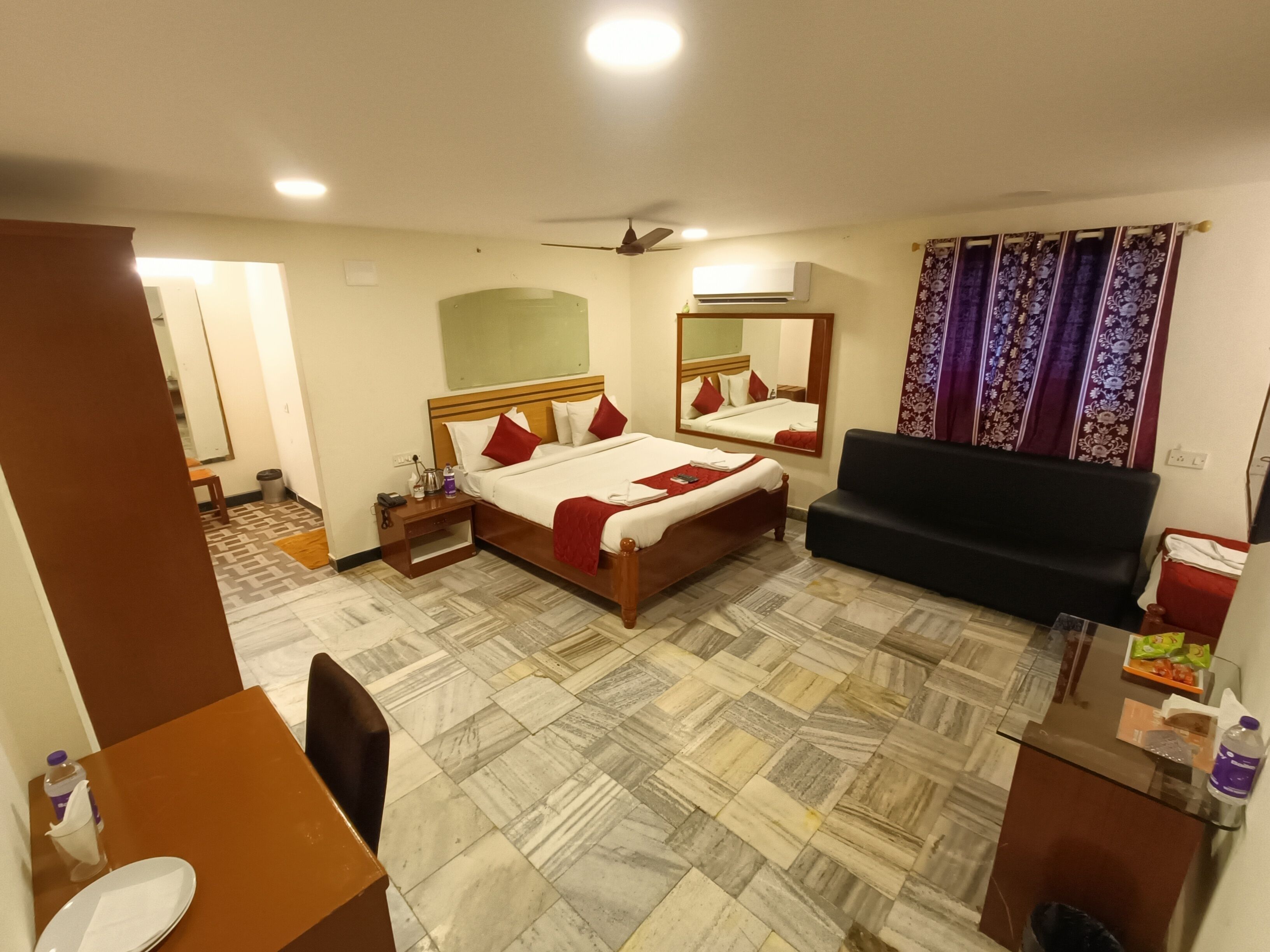 A hotel room with a bed, a sofa, a desk, and a bathroom.