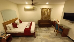 Una habitación de hotel con cama, sofá, televisor y escritorio.