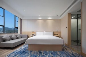 Una habitación de hotel moderna con una cama grande, un sofá y vistas a la montaña.