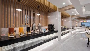 Un moderno vestíbulo de hotel con un mostrador de recepción de mármol negro, paneles de pared de listones de madera y una estación de café.