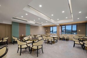 A spacious dining area with multiple tables and chairs, large windows with a view, and recessed ceiling lighting. - Xiang Wang Fu Hotel (Huaibei)