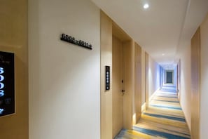 A hotel corridor with a carpeted floor, a digital display, and a door with a number sign. - Xiang Wang Fu Hotel (Huaibei)