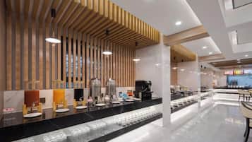 A modern hotel lobby with a long reception desk, wooden slatted ceiling, and a seating area with tables and chairs.