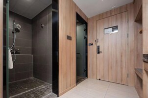 A modern bathroom with a shower, a wooden vanity, and a door with a handle.