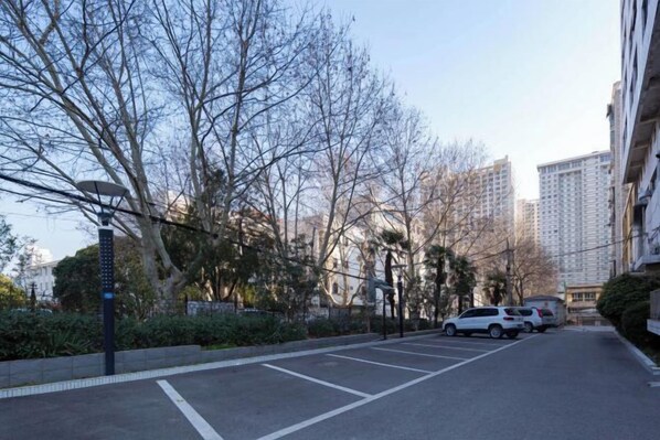 A street with parked cars, trees, and tall buildings. - Xiang Wang Fu Hotel (Huaibei)