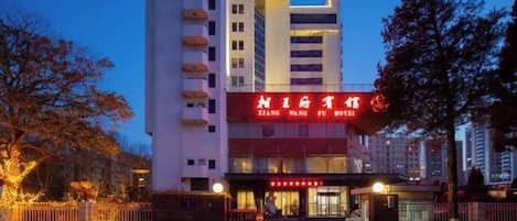 A hotel with a prominent red sign, multiple floors, and a gated entrance.