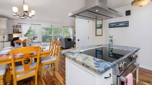 Una cocina moderna con una isla central, electrodomésticos de acero inoxidable y un comedor con sillas y mesa de madera.