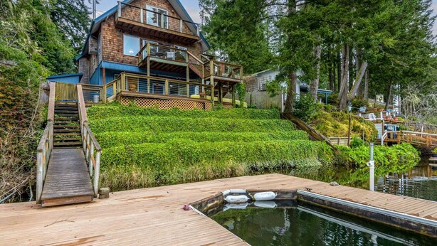 Una casa de dos pisos con terraza de madera y piscina.
