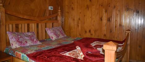 A wooden bed with a quilt and pillows, a wooden headboard, and a wooden wall.