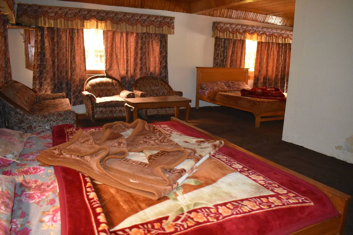 A cozy room with a bed, two armchairs, a wooden table, and a sofa.