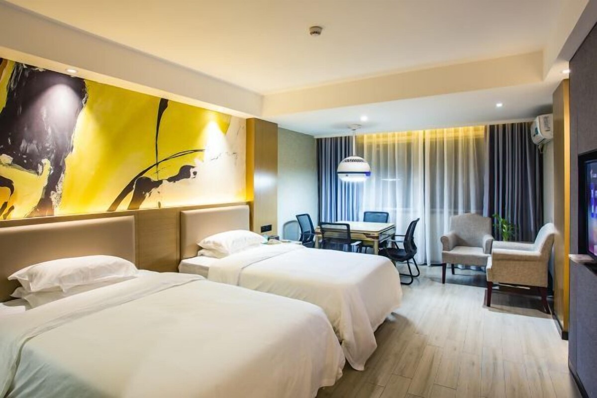Una habitación de hotel con dos camas, un escritorio, una silla y un televisor.