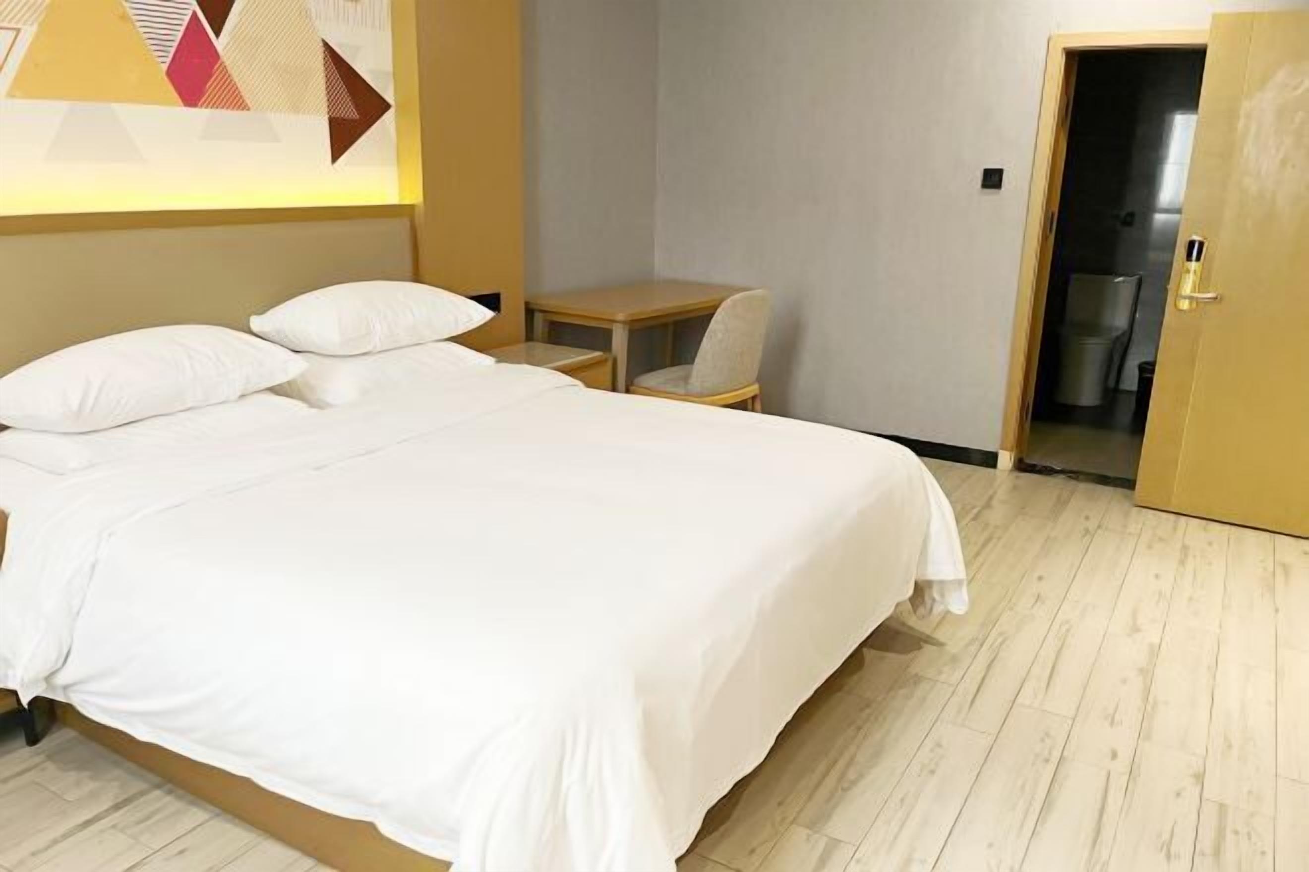Ein Hotelzimmer mit einem Bett, einem kleinen Tisch, einem Stuhl und einer Tür zu einem Badezimmer.