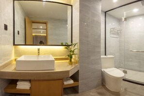 A modern bathroom with a large mirror, a white sink, a toilet, and a glass shower enclosure.