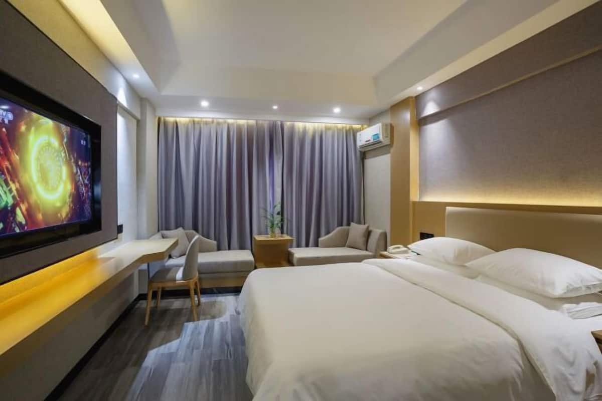 A hotel room with a bed, a desk, a chair, a TV, and a curtain.
