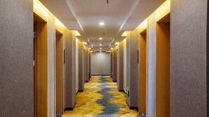 A hotel hallway with a patterned carpet, wooden doors, and recessed lighting. - Jinhua Hot Spring Hotel (Luchuan)