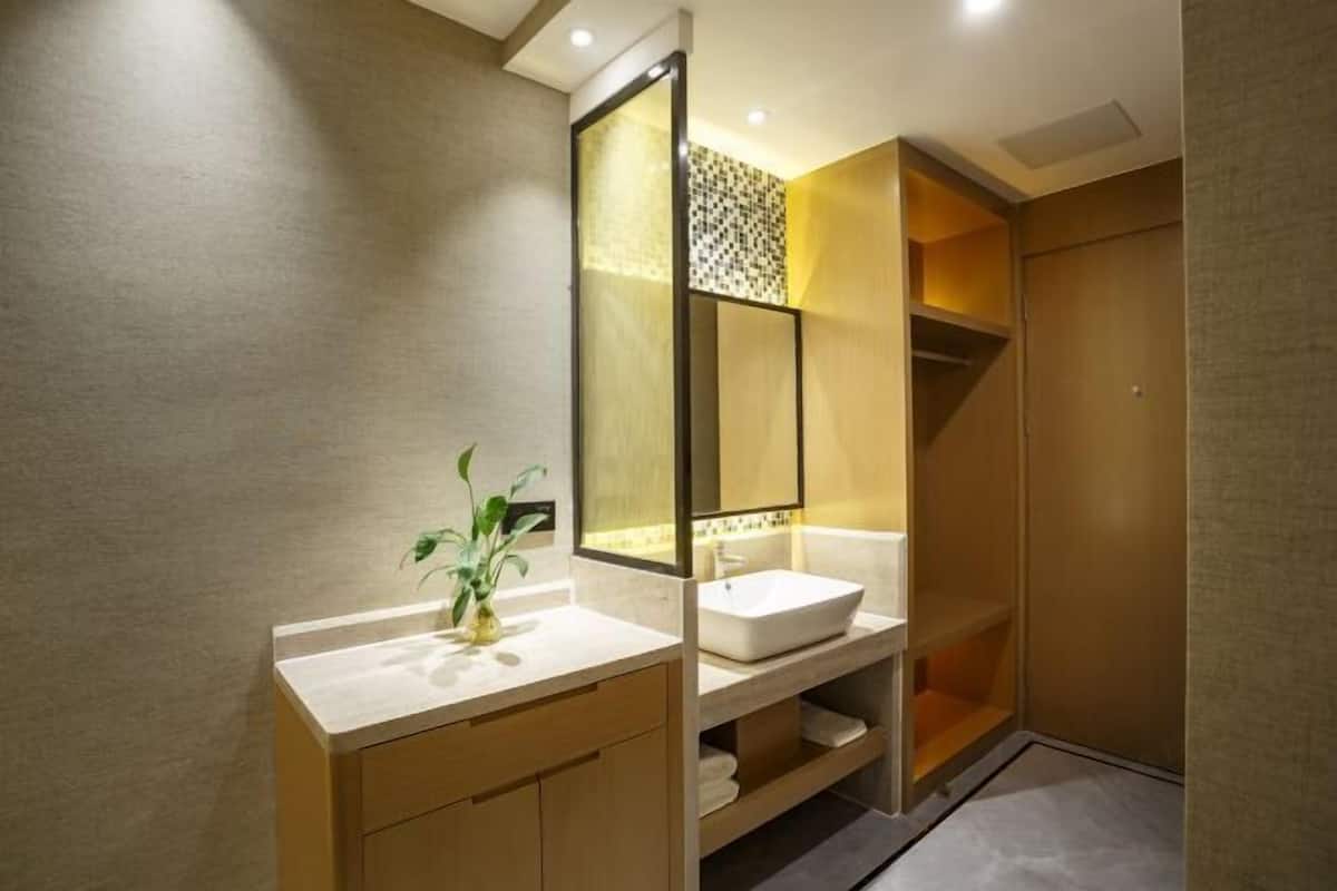 A modern bathroom with a large mirror, a sink, and a plant.