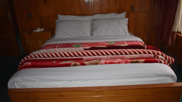 Un lit en bois avec une literie blanche et une couverture à rayures rouges et blanches.
