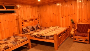 A wooden room with a bed, a chair, and a small table. - The Kylix (Balakot)