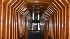 A wooden hallway with a patterned floor and a door at the end. - The Kylix (Balakot)
