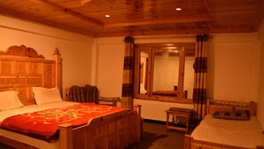 A wooden bedroom with two beds, a mirror, and a small table. - The Kylix (Balakot)