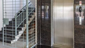 A modern elevator with a metallic finish, a glass-enclosed stairwell, and a security keypad on the wall. - Pinnacle Serviced Apartments (Bengaluru)