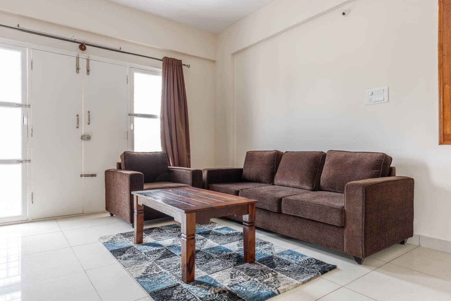 A living room with a brown sofa, a wooden coffee table, and a patterned rug.
