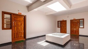 A hotel lobby with wooden doors, a central display, and a high ceiling with skylights. - Pinnacle Serviced Apartments (Bengaluru)