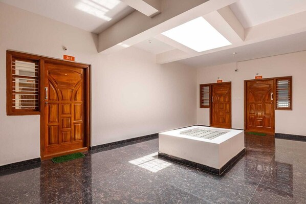 Um saguão de hotel com portas de madeira, um expositor central e um teto alto com claraboias.