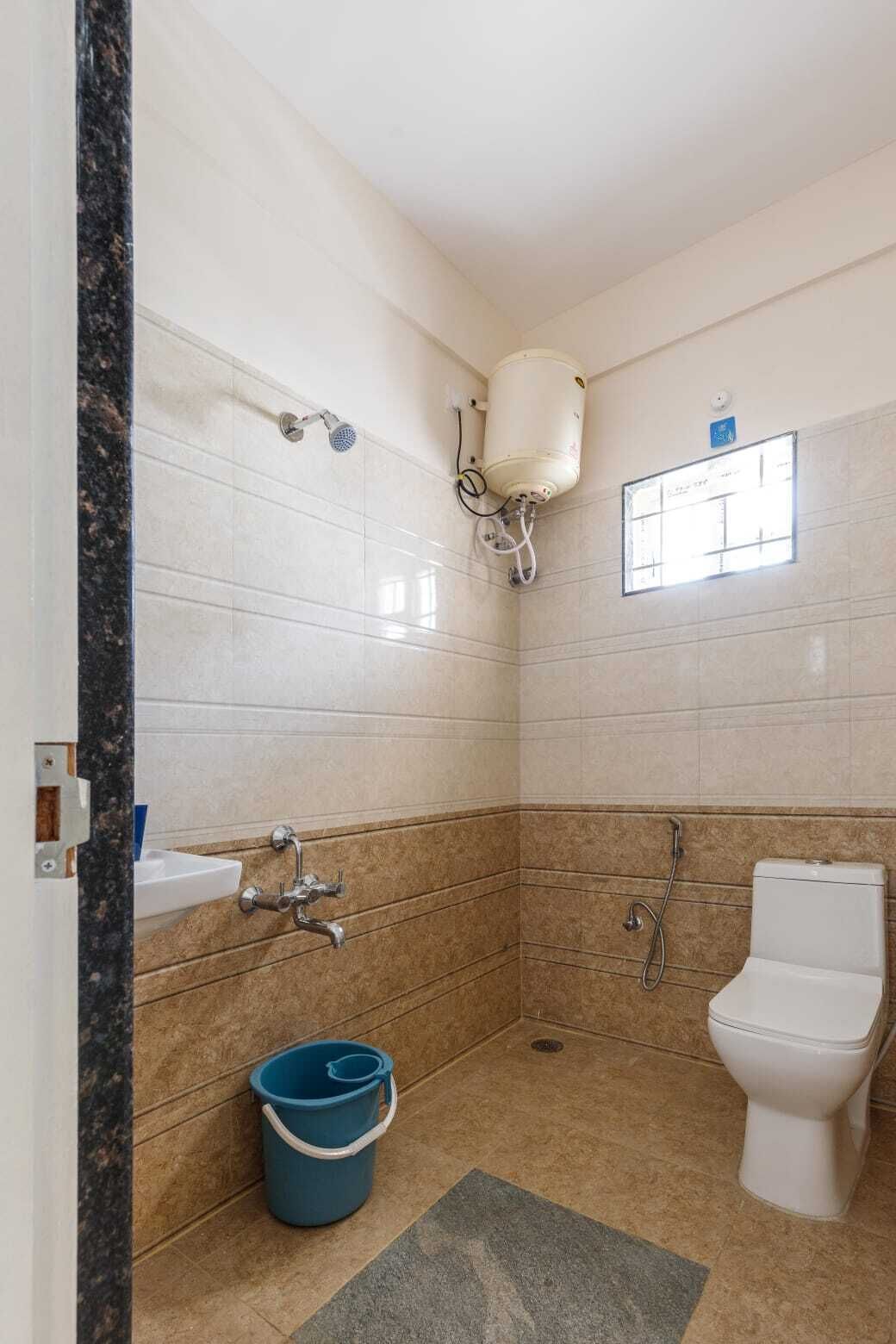 A bathroom with a toilet, sink, shower, and a water heater.