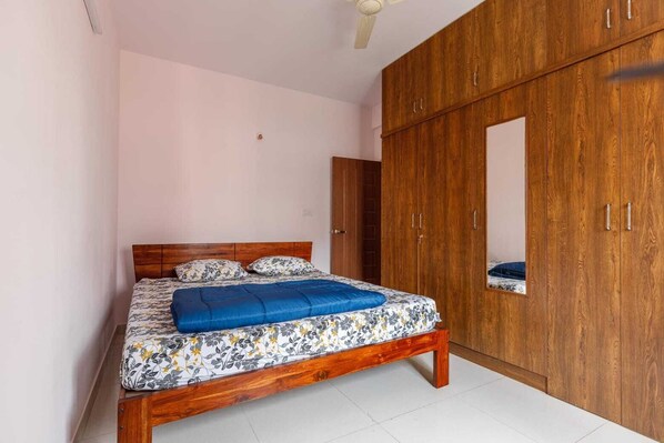 Un dormitorio con una cama de madera, un armario y un espejo.